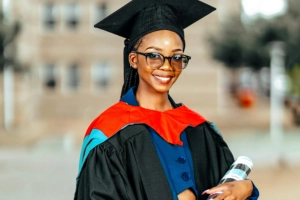 another woman scholar dressed in graduation gound and cap